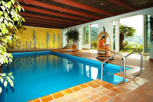 a man sitting in a chair next to a swimming pool at Panorama Residence Öhlerhof in Lagundo