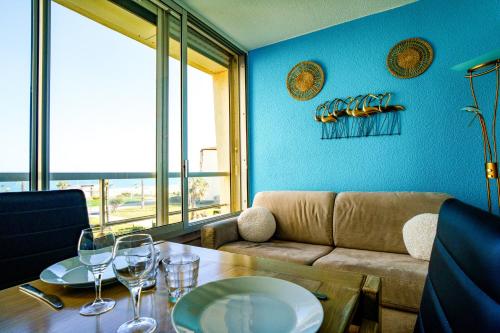 - un salon avec un canapé et une table avec des verres à vin dans l'établissement Les pieds dans le sable, au Barcarès