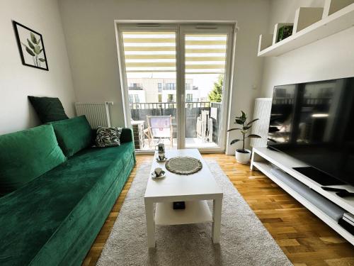 a living room with a green couch and a tv at Klify Jastrzębie Premium in Jastrzębia Góra