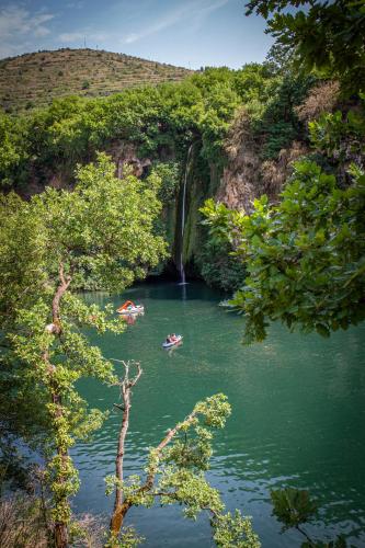 a group of people in boats in a river with a waterfall at Camping de la Base Nautique in Saint-Rome-de-Tarn