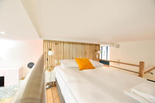 a bedroom with a large white bed with a yellow pillow at Hyper-Centre Studio Lekain UnSejourANantes in Nantes