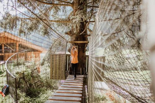 a woman standing on a suspension bridge near a tree at Familienhotel Huber in Valles
