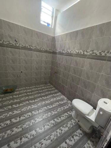 ein Badezimmer mit Toilette und gefliestem Boden in der Unterkunft Fassinou in Cotonou