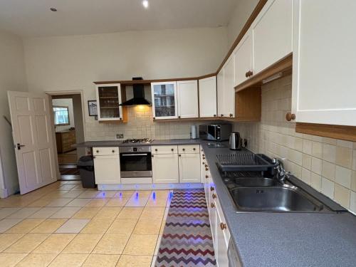a kitchen with white cabinets and a sink at Elm Lodge in Plymouth