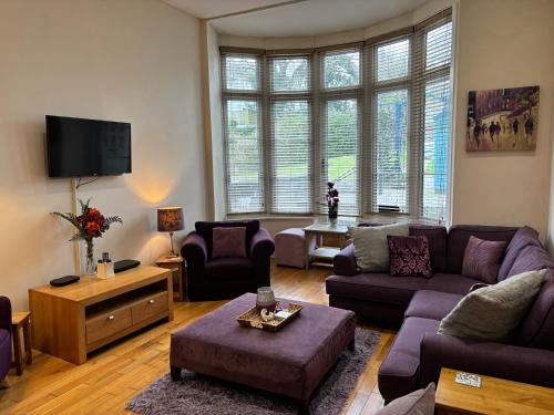 a living room with purple couches and a tv at Elm Lodge in Plymouth