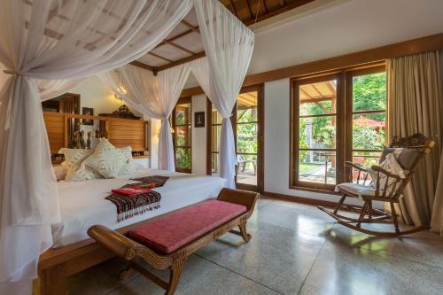 sypialnia z dużym białym łóżkiem i krzesłem w obiekcie Taman Sari Bali Resort and Spa w mieście Pemuteran