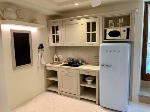 a white kitchen with a refrigerator and a microwave at Da Gianni e Villa Annamaria in Arco