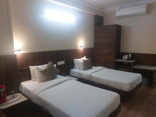 a hotel room with two beds and a table at Hotel Shikhar Palace in Jabalpur