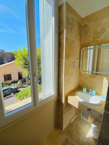une salle de bain avec un lavabo et une fenêtre dans l'établissement Clair Matin - Appartement Balcon - Maison privée, à Lamalou-les-Bains