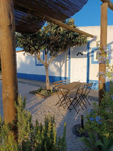 a patio with a table and chairs and a tree at Casas do Montinho in Melides