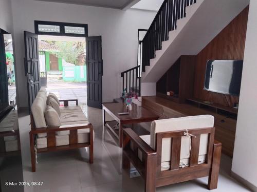 a living room with a couch and a tv and stairs at Majid's Homestay Solo in Kartosuro