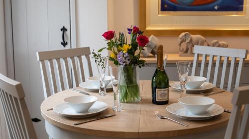 drewniany stół z kwiatami i butelką wina w obiekcie Gordon Cottage w mieście Chipping Campden