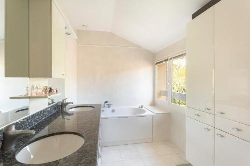 La salle de bains blanche est pourvue de 2 lavabos et d'un lavabo. dans l'établissement Maison au calme près de Versailles, à Louveciennes