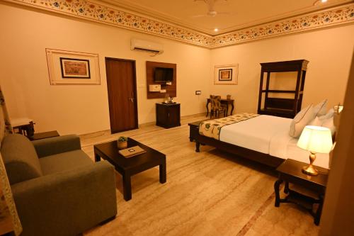 a bedroom with a bed and a couch and a chair at The Shergarh in Khilchipur