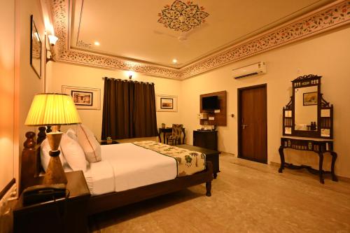 a bedroom with a bed and a lamp in a room at The Shergarh in Khilchipur