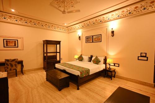 a bedroom with a bed and a table and a chair at The Shergarh in Khilchipur