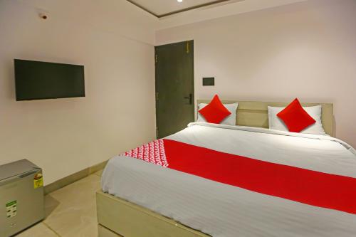 a bedroom with a bed with red pillows and a tv at Super Hotel O Botcha Convection in Visakhapatnam