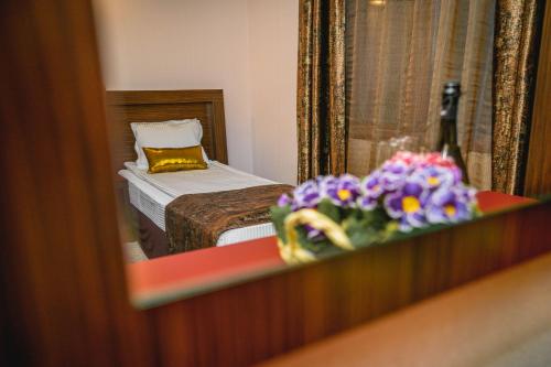 a reflection of a bedroom with a bed and flowers at Eleganza Family Hotel - Free Parking in Sofia