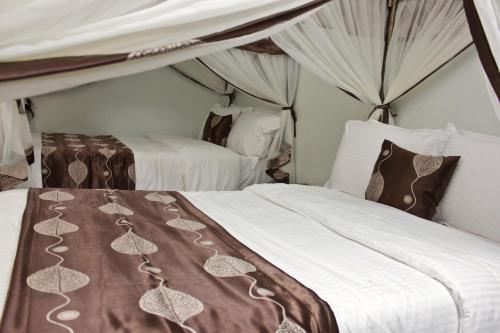 1 dormitorio con 2 camas con sábanas blancas y marrones en Hadassah Hotel, en Nairobi