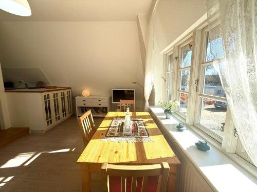 a dining room with a wooden table and a window at Reetstübchen in Nieblum