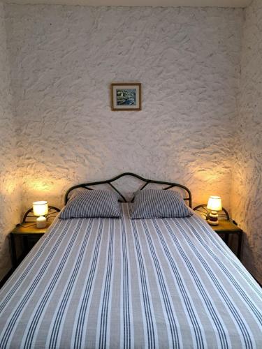 un lit rayé avec deux lampes sur deux tables dans l'établissement Agréable maison au Pyla sur mer 6 personnes, à La Teste-de-Buch
