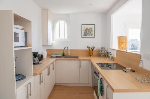 a kitchen with white cabinets and a sink and a microwave at Les Terrasses 2 in Leucate-Plage