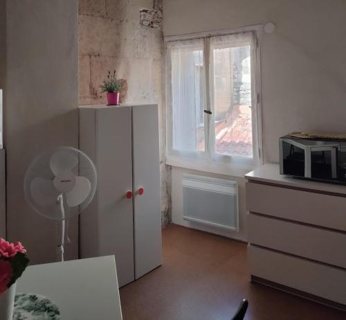 - une cuisine avec une armoire blanche et un four micro-ondes dans l'établissement Studio Romarin au pied des Arènes, à Arles