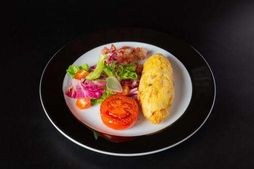 a plate of food with a salad and a egg and tomato at GRANFERTE Phnom Penh Hotel in Phnom Penh