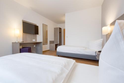 a white bedroom with a bed and a television at Bamberg Inn in Hallstadt