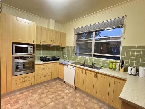 a kitchen with wooden cabinets and a sink and a window at 34 Room in Epping