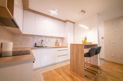 a kitchen with white cabinets and a table and chairs at Apartment 5 Star - Free Parking in Lukavica