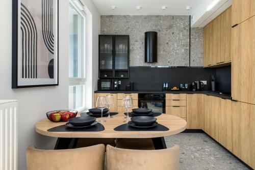 a kitchen with a wooden table and chairs at Kairos Apartments -Sky - darmowy parking podziemny, ścisłe centrum in Katowice
