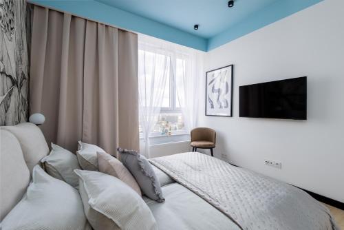 a bedroom with a bed with pillows and a television at Kairos Apartments -Sky - darmowy parking podziemny, ścisłe centrum in Katowice