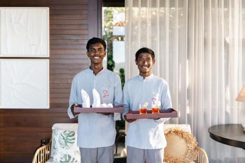 zwei Männer in weißen Uniformen halten ein Tablett mit Essen in der Unterkunft LohonoStays Amani Villa 11A in Coonoor