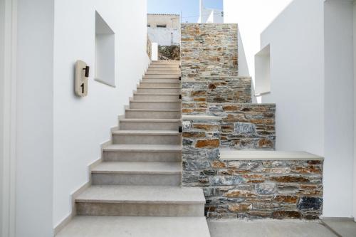 a staircase in a house with a stone wall at Kythnos Blue - Suite 4 Luxurious, Sea Front in Kithnos