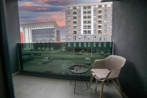 a balcony with two chairs and a table and a large window at Apartment 5 Star - Free Parking in Lukavica
