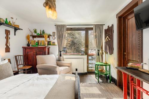 a bedroom with a bed and a chair and a window at Casa cu Amintiri - Authentic Cozy Cottage in Bran