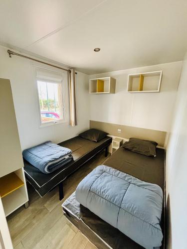 une petite chambre avec deux lits et une fenêtre dans l'établissement Le 510 mobil-home, à Parentis-en-Born