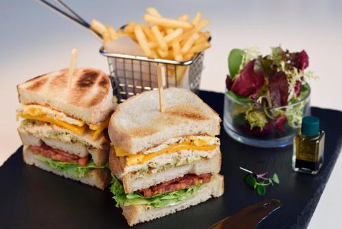 a sandwich cut in half on a table with a basket of fries at Southern Sun Abu Dhabi in Abu Dhabi