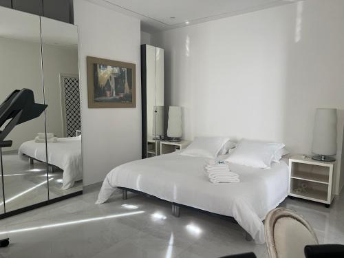 une chambre blanche avec un grand lit et un miroir dans l'établissement Appartement Haut Standing 5 pièces Cannes centre, à Cannes