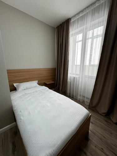 Una cama en un dormitorio con una ventana grande. en Uide hotel, en Almaty