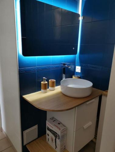 La salle de bains est pourvue d'un lavabo et d'un mur bleu. dans l'établissement Bel appartement face Océan, à Soulac-sur-Mer