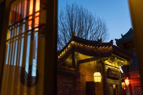 a reflection of a building with a tree in a window at Datong Yunzhong Traditional Courtyard in Datong