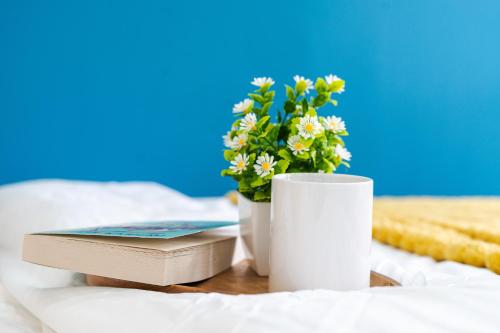 a book and a cup and a vase with flowers at Open Mind Property - Hot Tub, 8 Guests & Free Parking in Portsmouth