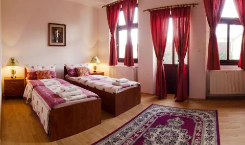 two beds in a room with red curtains and a rug at The Rooms by Dalia in Košice