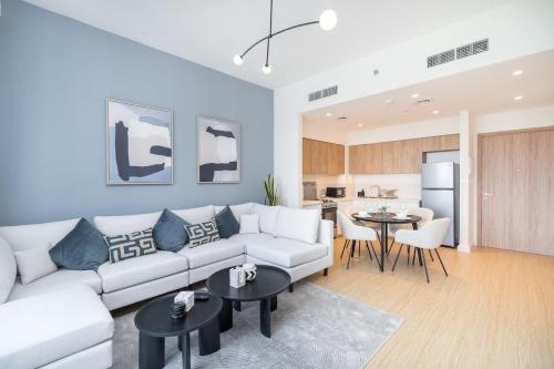 a living room with a white couch and a kitchen at Free housekeeping visits during your stay - StayShort - Chic 1-Bed for 4 in Prime Dubai Hills Location in Dubai