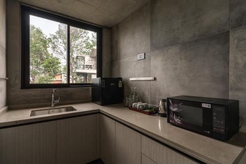 eine Küche mit Mikrowelle, Spüle und Fenster in der Unterkunft LohonoStays Amani Villa 11B in Coonoor