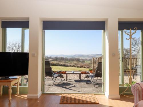 a living room with a sliding glass door to a patio at The Shippon at Wyke Farm in Axminster