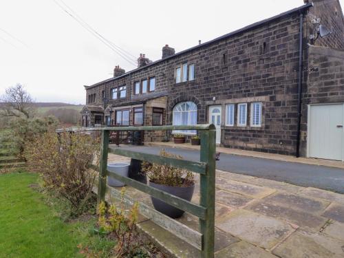 an old brick building with a fence in front of it at Popples Barn in Hebden Bridge