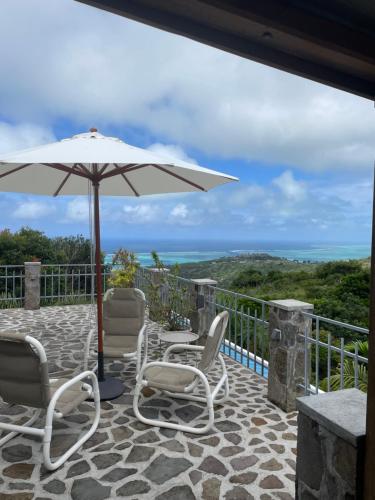 a patio with a table and chairs and an umbrella at Charming Villas in Rodrigue in Tambe